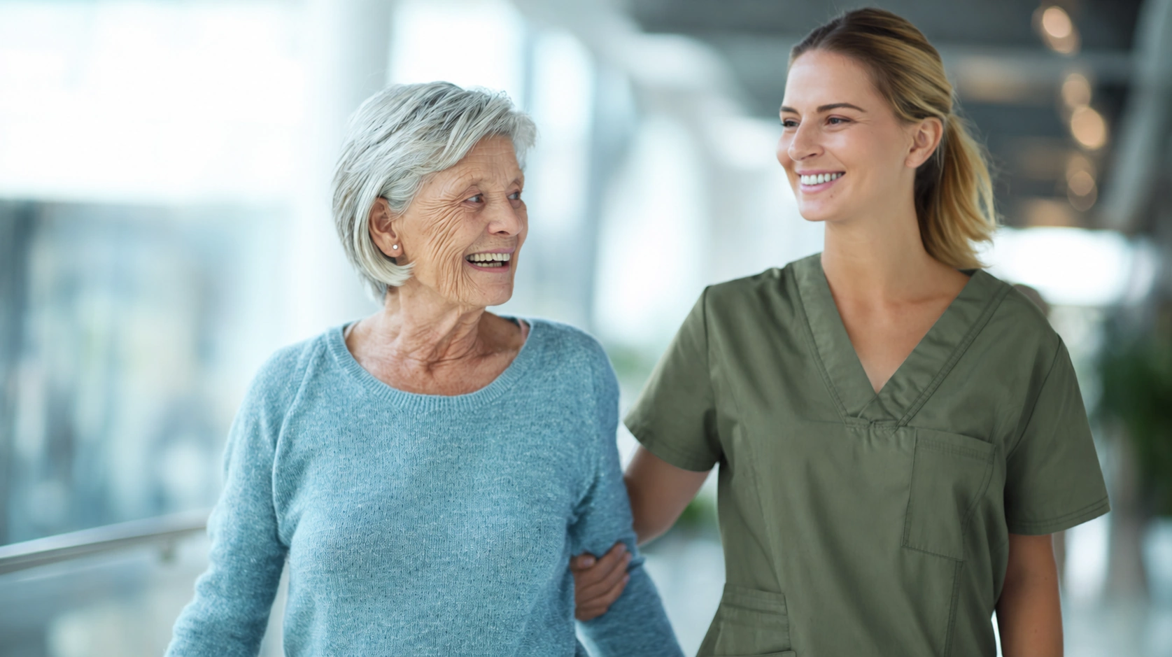 smiling elderly woman walks with kind caregiver's hand around her arm