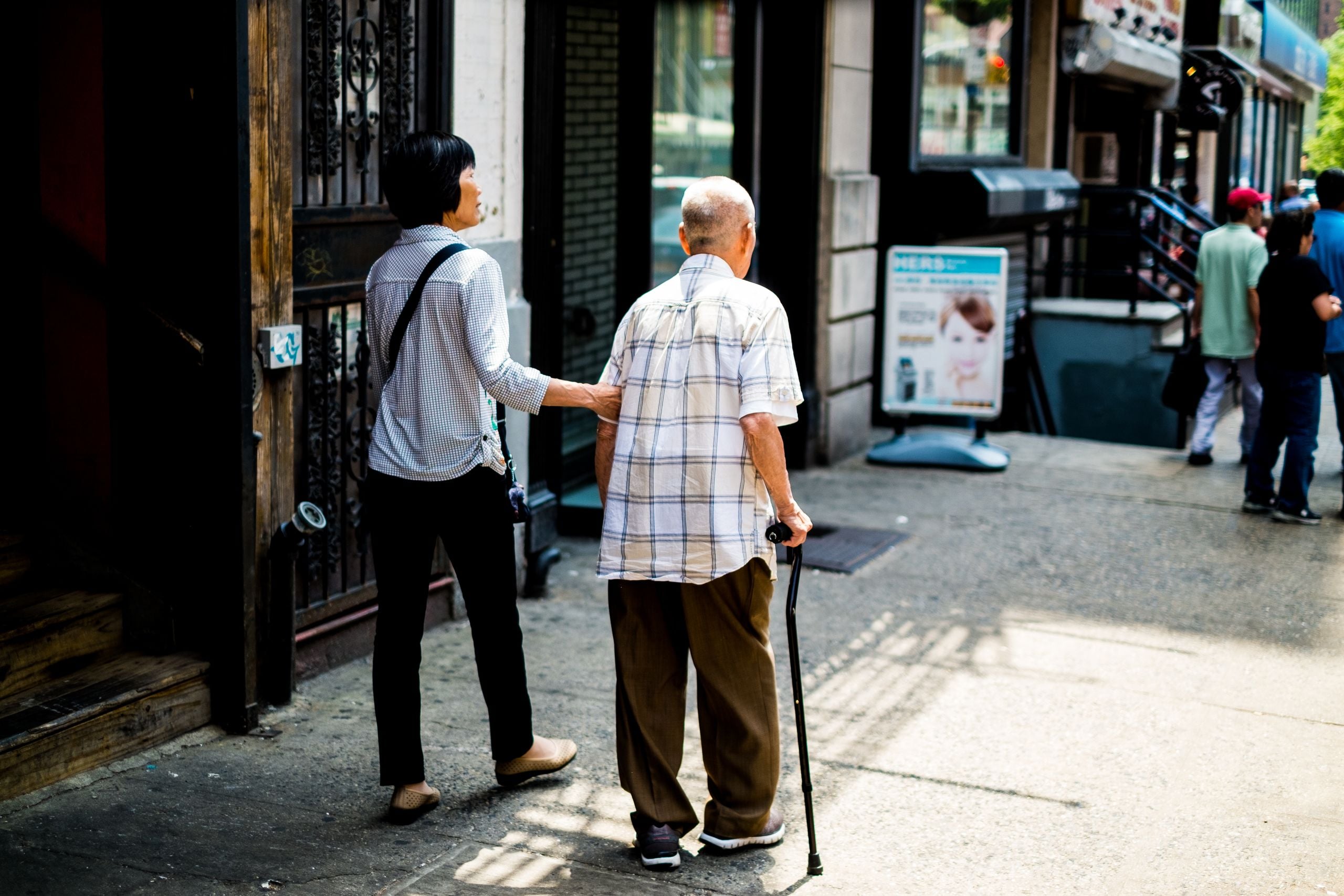 Caregiver steadying a senior with a cane during a walk, home care in Northport, NY