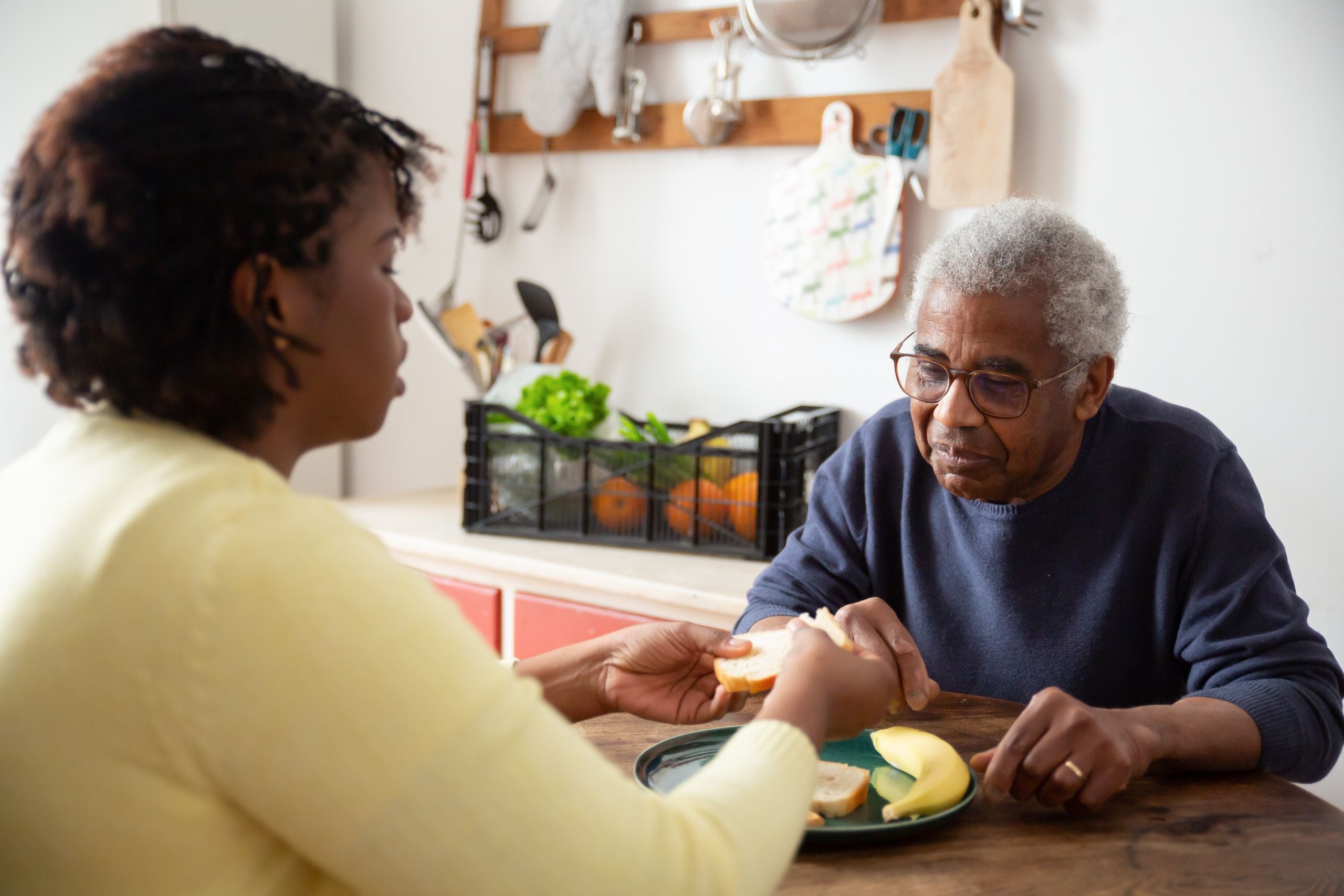 Caregiver helping a senior enjoy a meal at home, home care in Great Neck, NY