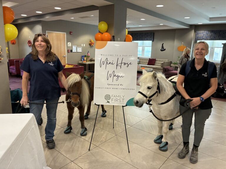 Handlers with a brown and a white miniature horse next to the Mini Horse Magic sign sponsored by Family First
